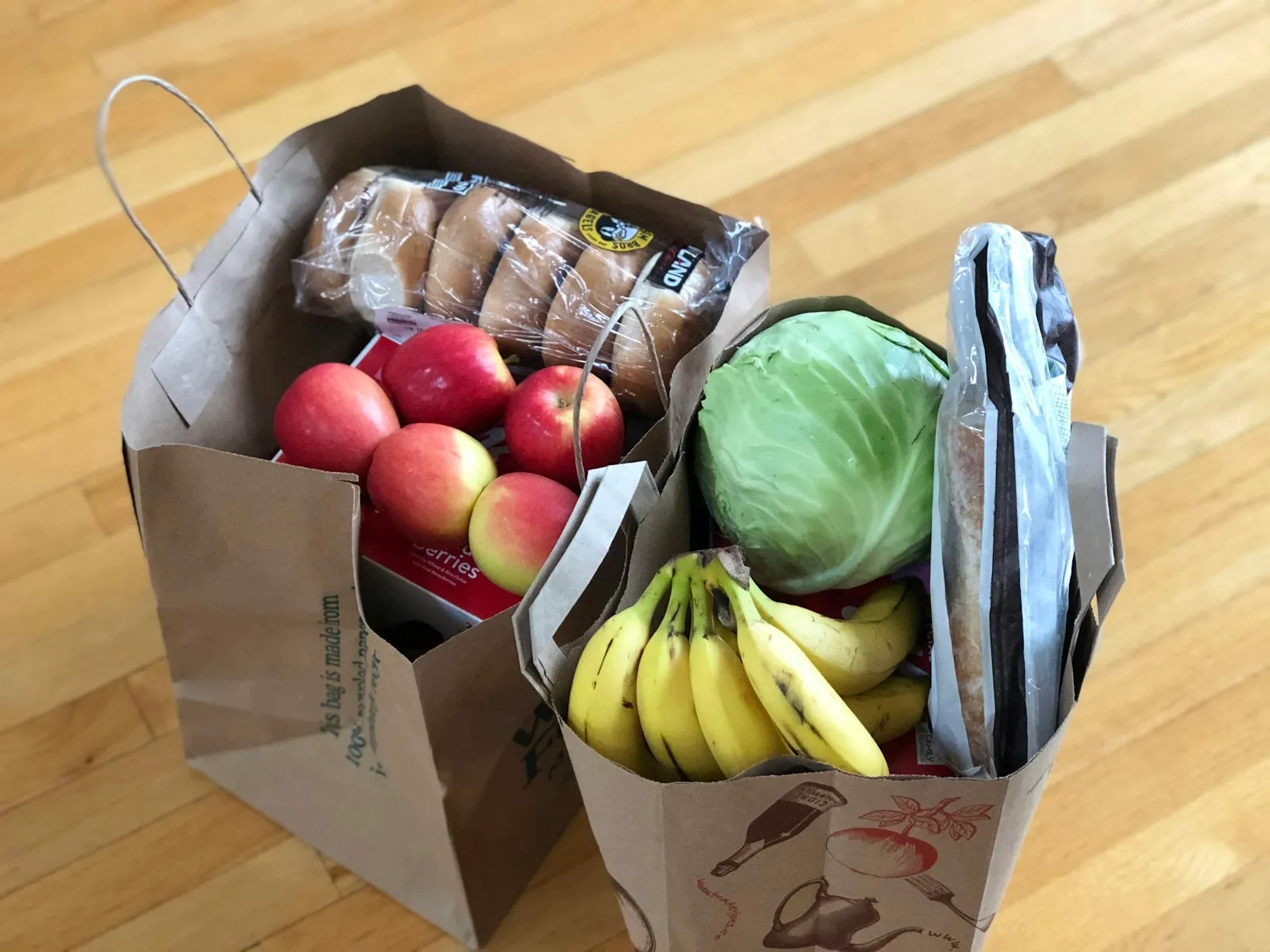 Paper bags filled with apples, bananas, bread and greens